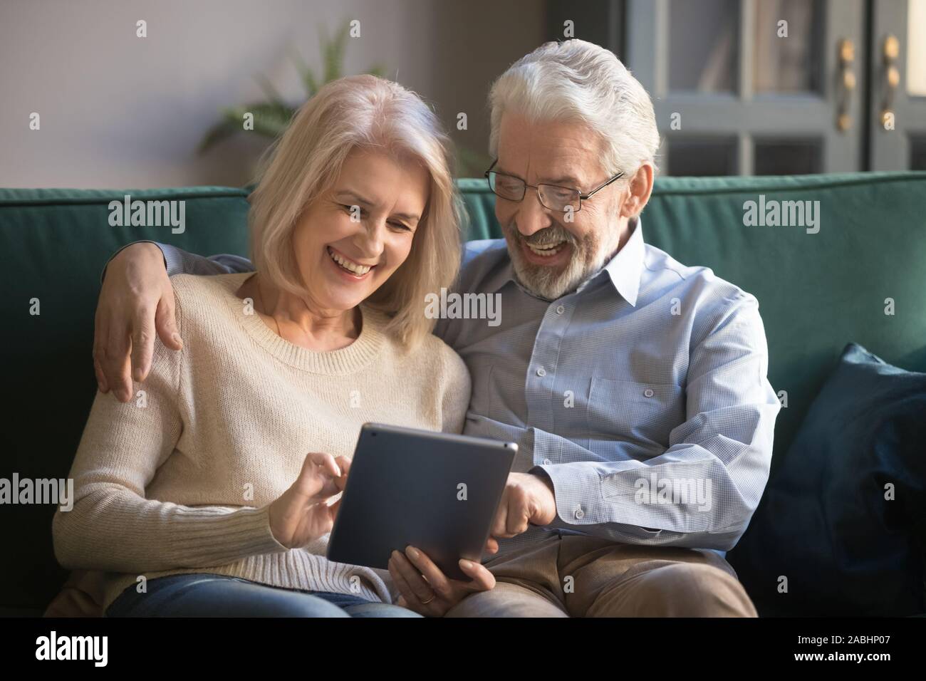 Cheerful elderly spouses having fun using digital tablet Stock Photo
