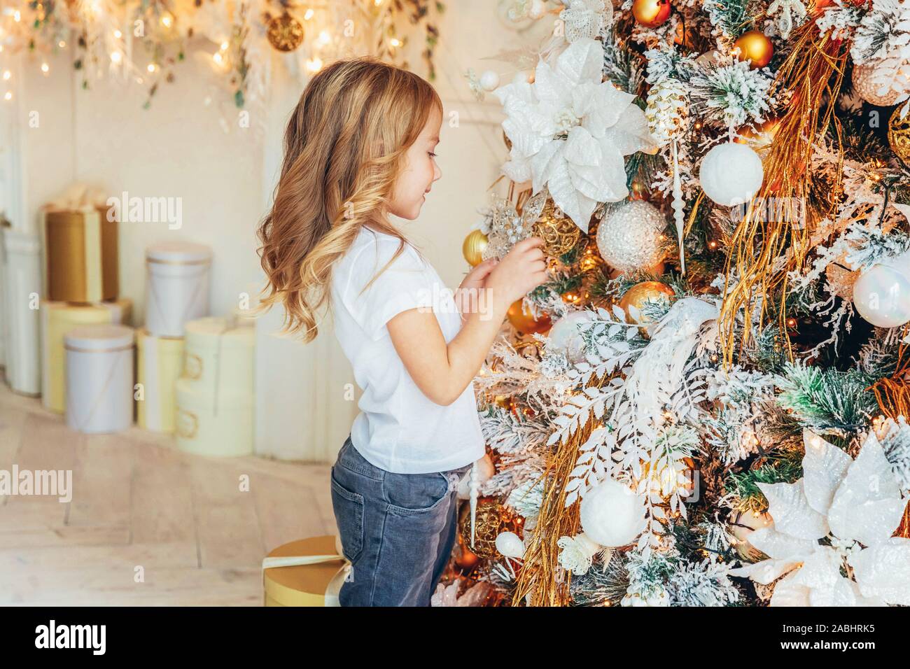 Little girl decorating Christmas tree on Christmas eve at home. Young