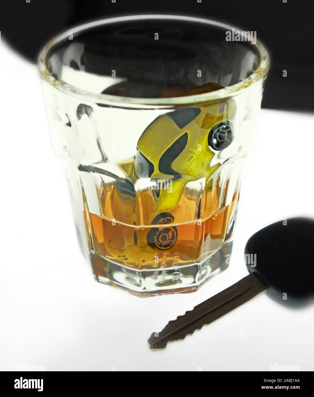 Small car drowned in a glass of alcohol. Car key. Stock Photo