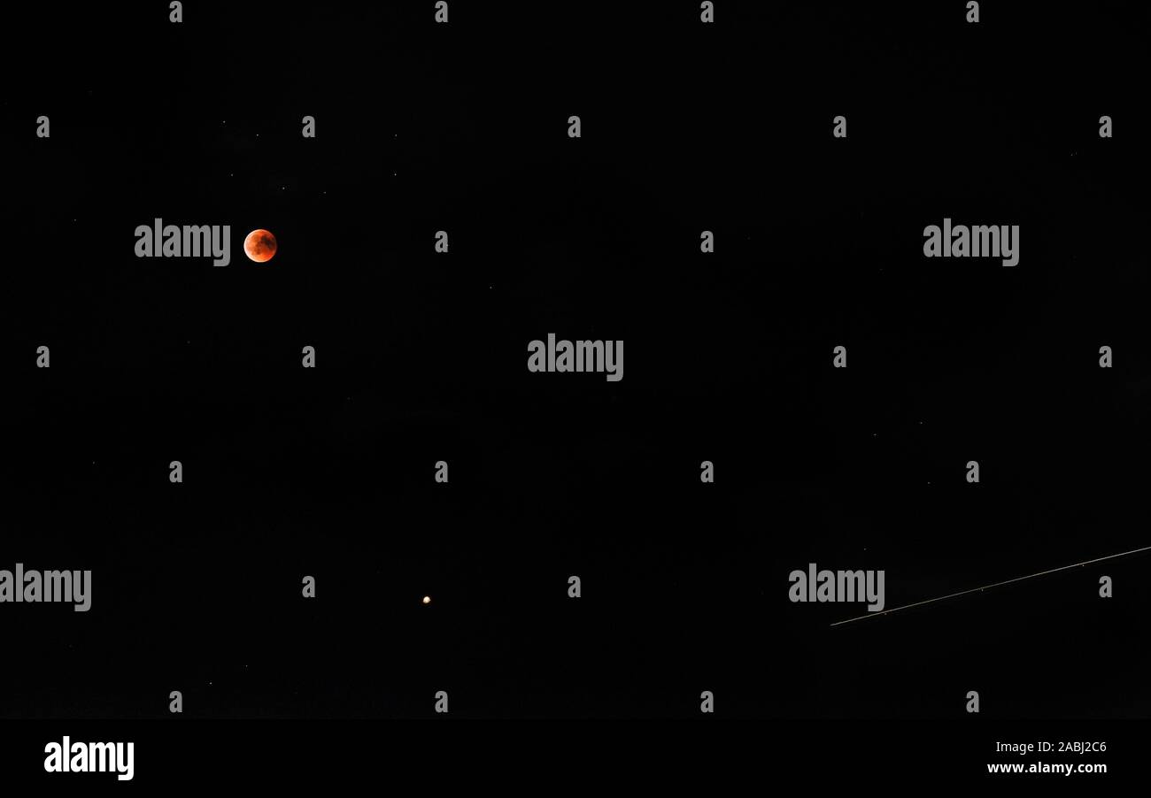 Bloody red moon eclipse with comet trail on starry black sky background Stock Photo