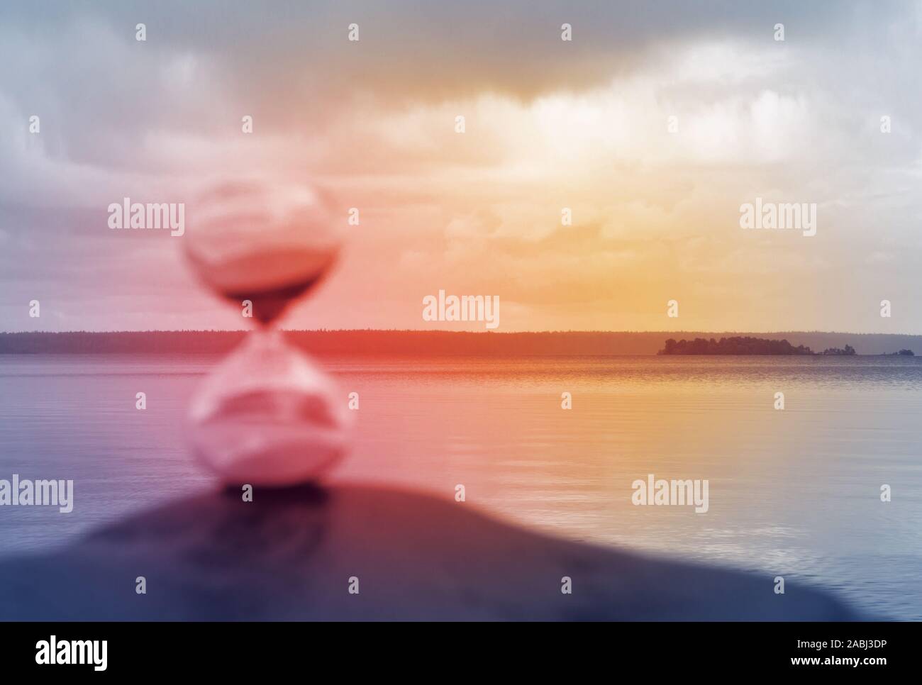 Blurred hourglass on a rock, illuminated in red as a concept of lost time. Stock Photo
