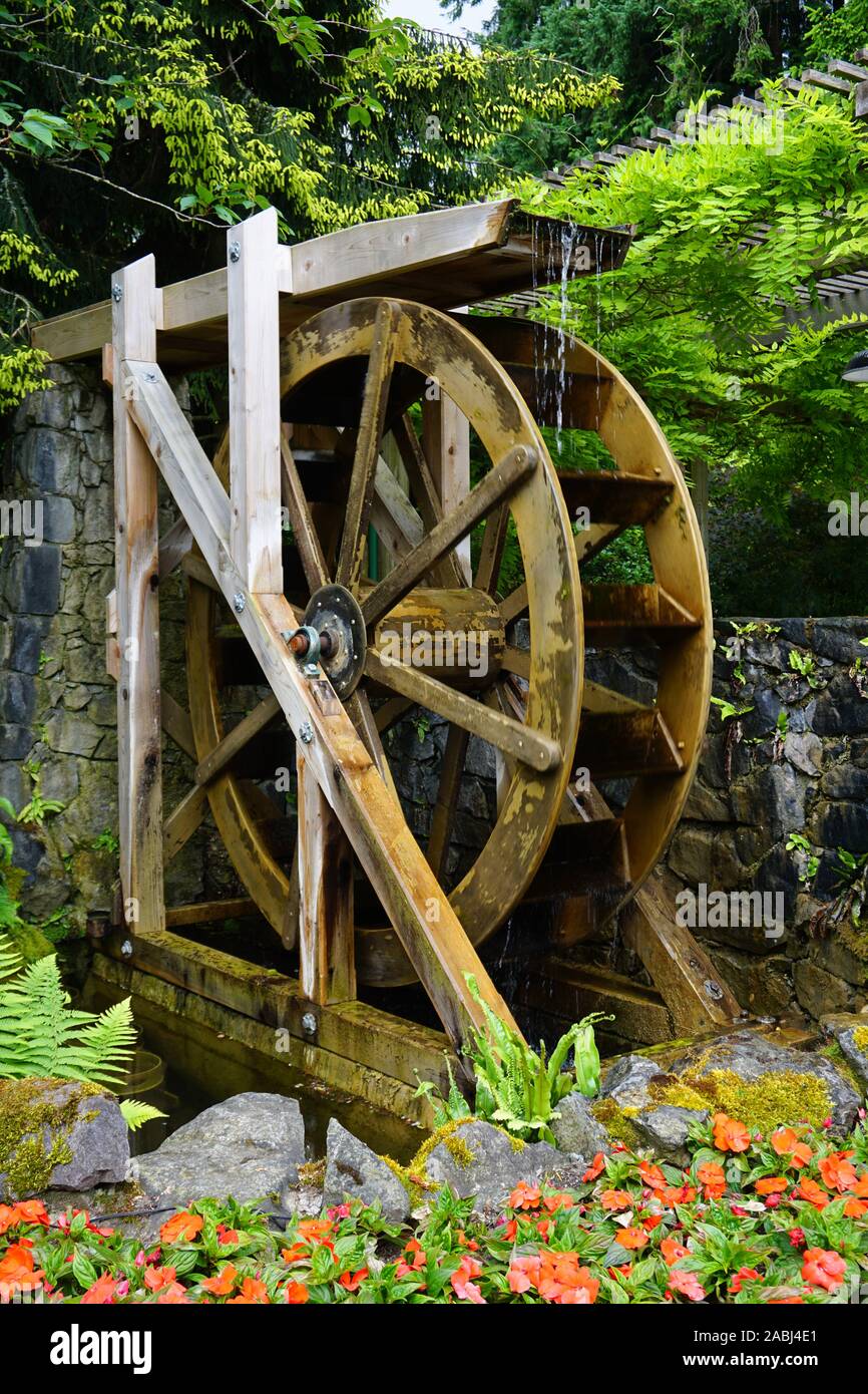 A motion-blurred water wheel with flowers in the foreground Stock Photo