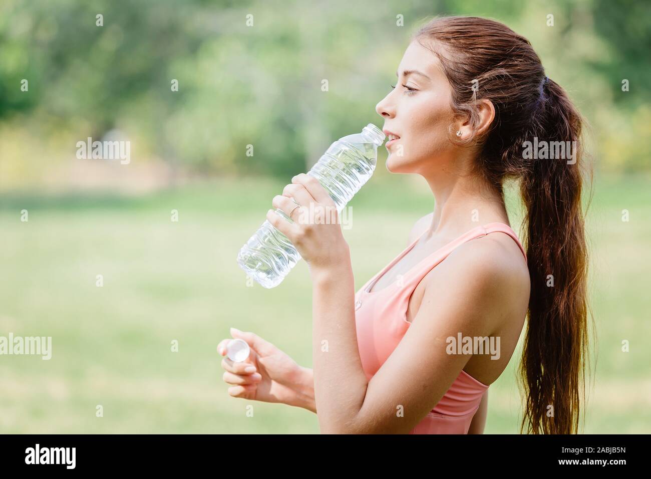 Thirsty beautiful sport women model handle drink clean drinking water outdoor after exercise. Stock Photo