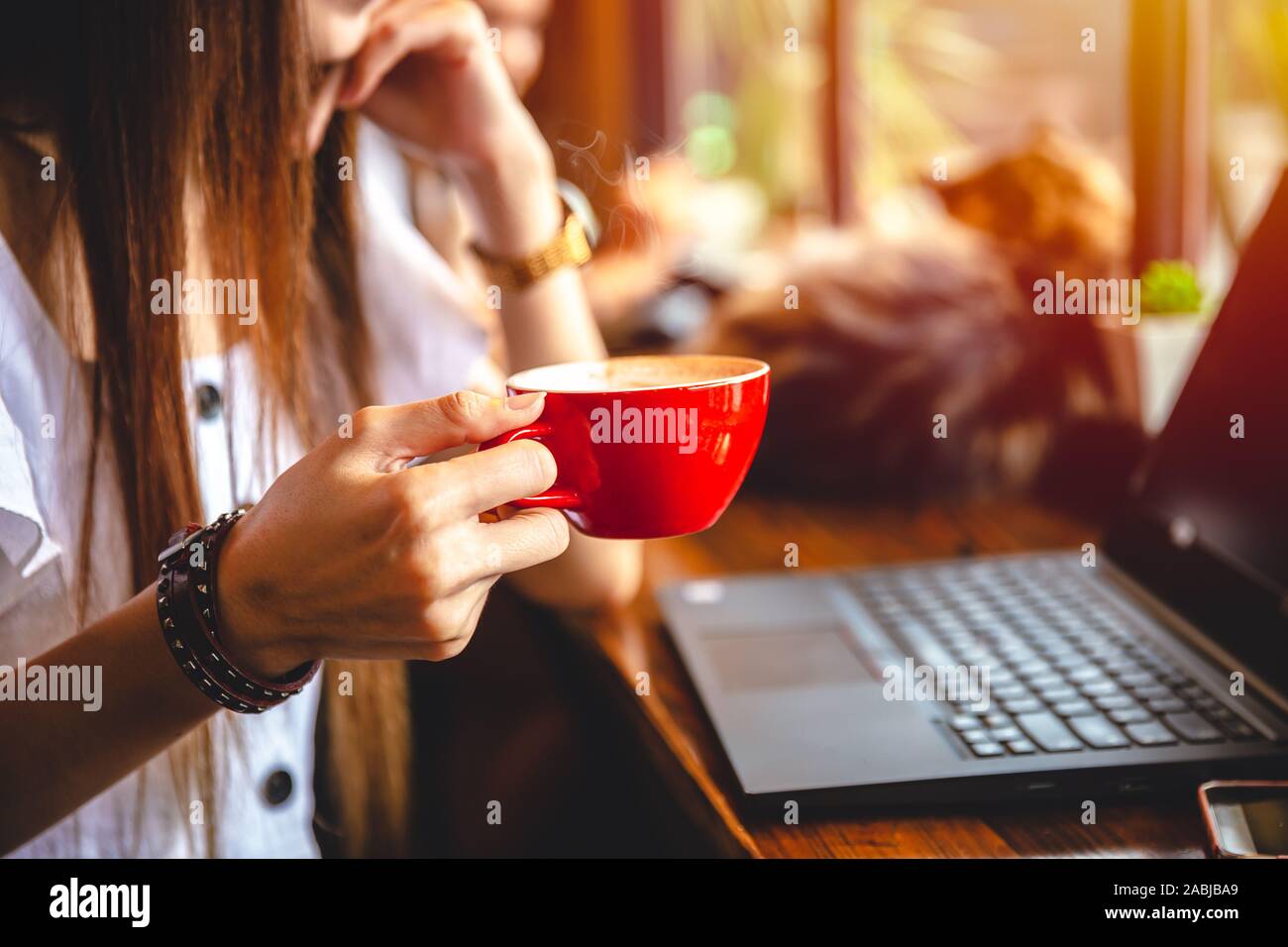 Freelace businesswoman hand holding coffee mug working with laptop computer on wooden table for business cafe hopper lifestyle. Stock Photo