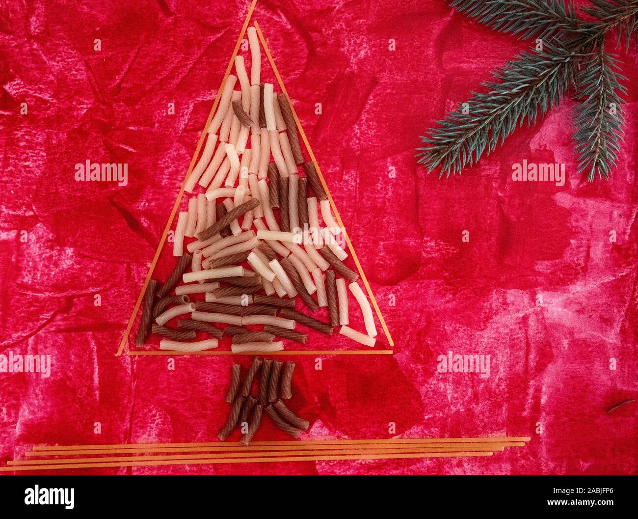 Christmas tree made of gluten free rise and quinoa pasta and christmas decoration laid on abstract red hand drown background. Perfect for Christmas, N Stock Photo