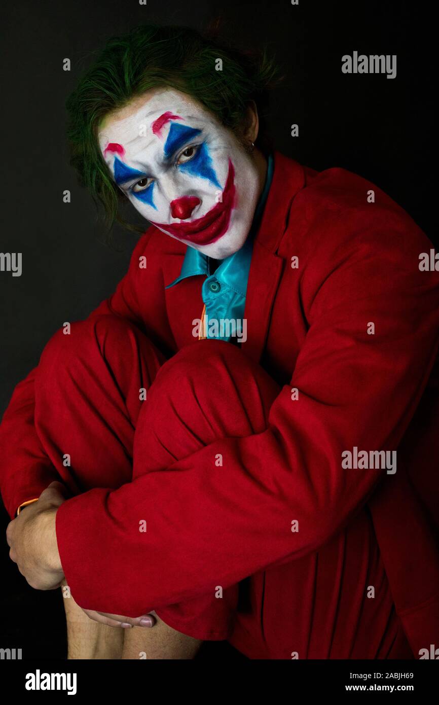Man impersonating the Joker. Portrait of a man in a suit with clown makeup  and green hair. Joker cosplay Stock Photo - Alamy