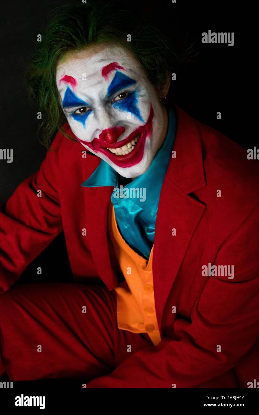 Man impersonating the Joker. Portrait of a man in a suit with clown makeup  and green hair. Joker cosplay Stock Photo - Alamy