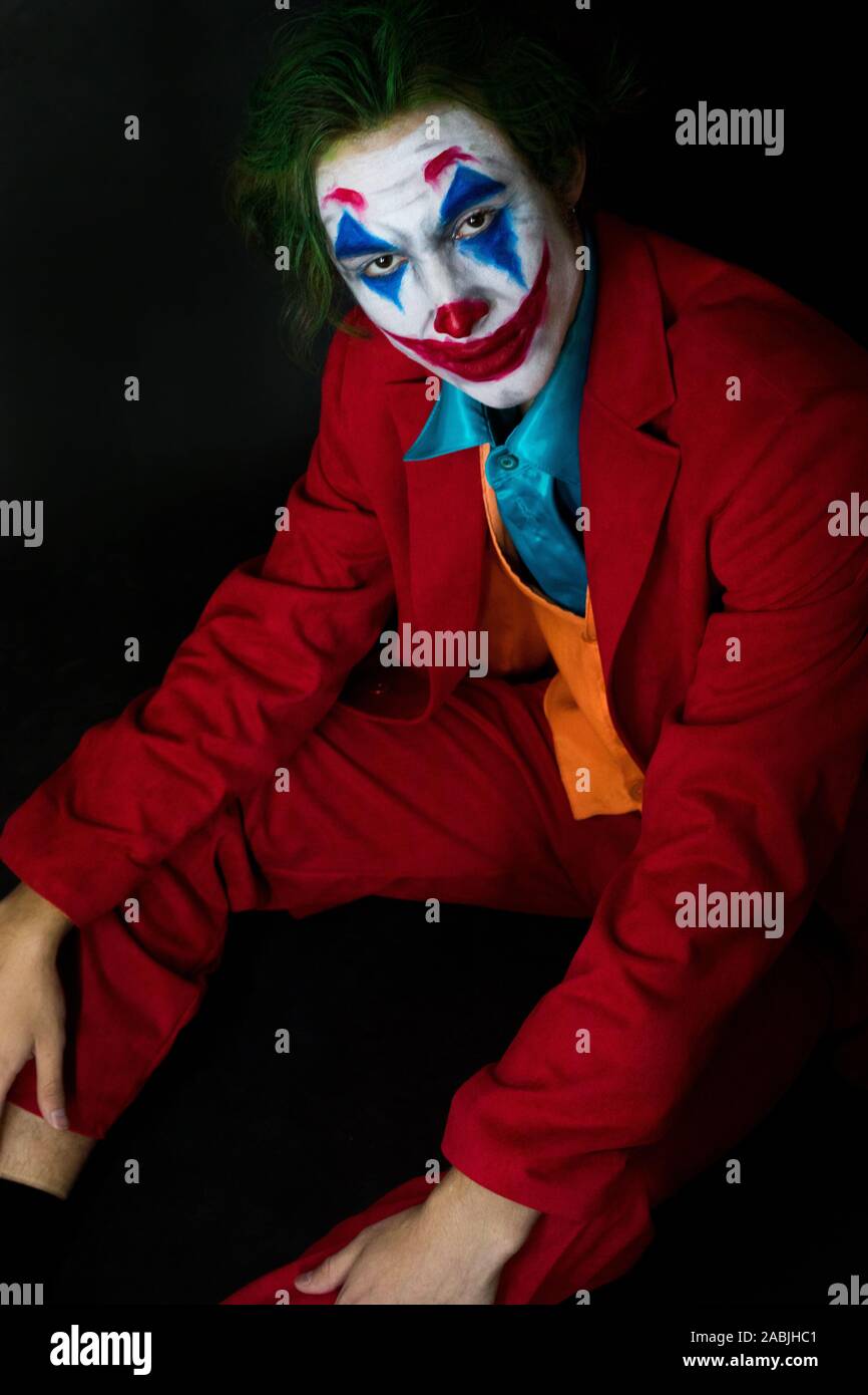 Man impersonating the Joker. Portrait of a man in a suit with clown makeup  and green hair. Joker cosplay Stock Photo - Alamy