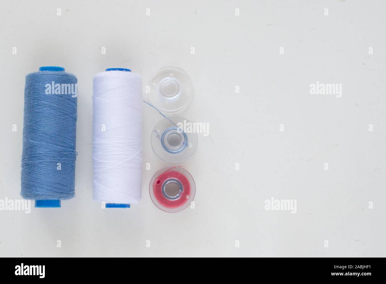 Sewing accessories on a light background close-up. Multi-colored spools of thread Stock Photo
