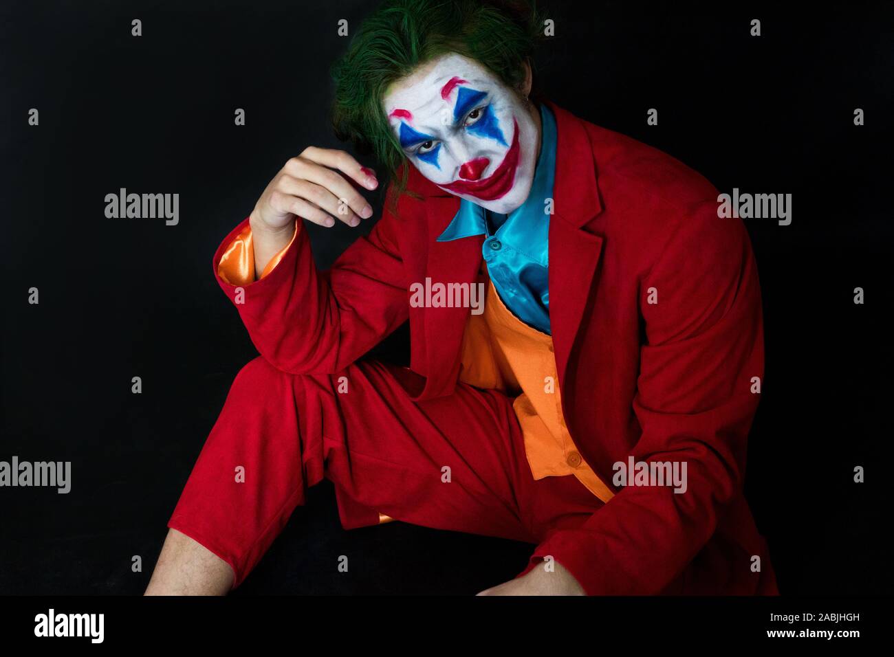 Man impersonating the Joker. Portrait of a man in a suit with clown makeup  and green hair. Joker cosplay Stock Photo - Alamy