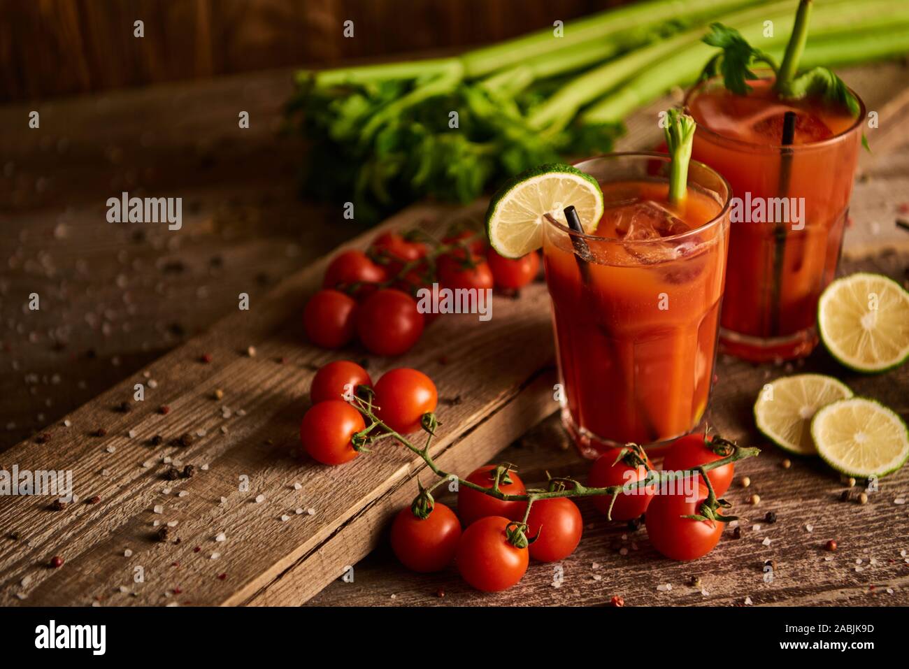 bloody mary cocktail in glasses on wooden background with salt, pepper