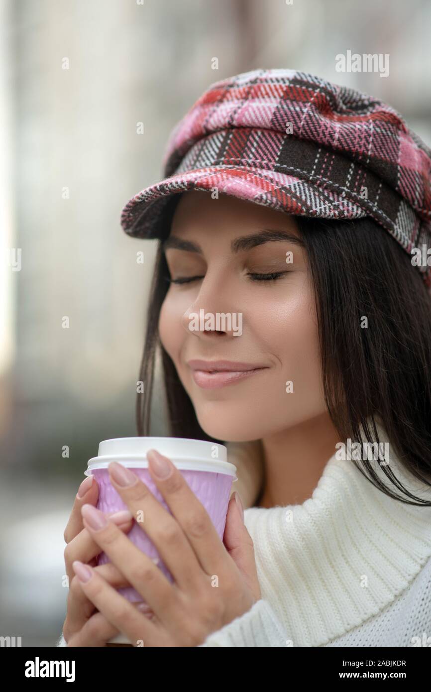 Happy dark haired woman smelling her delicious coffee Stock Photo