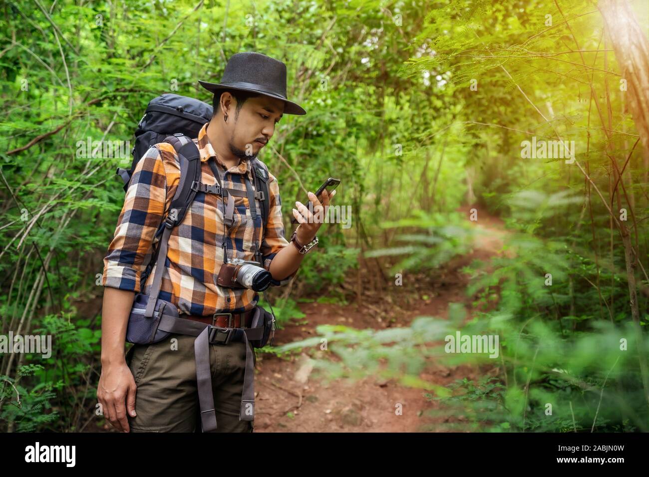 man traveler with backpack using smartphone in the natural forest Stock Photo