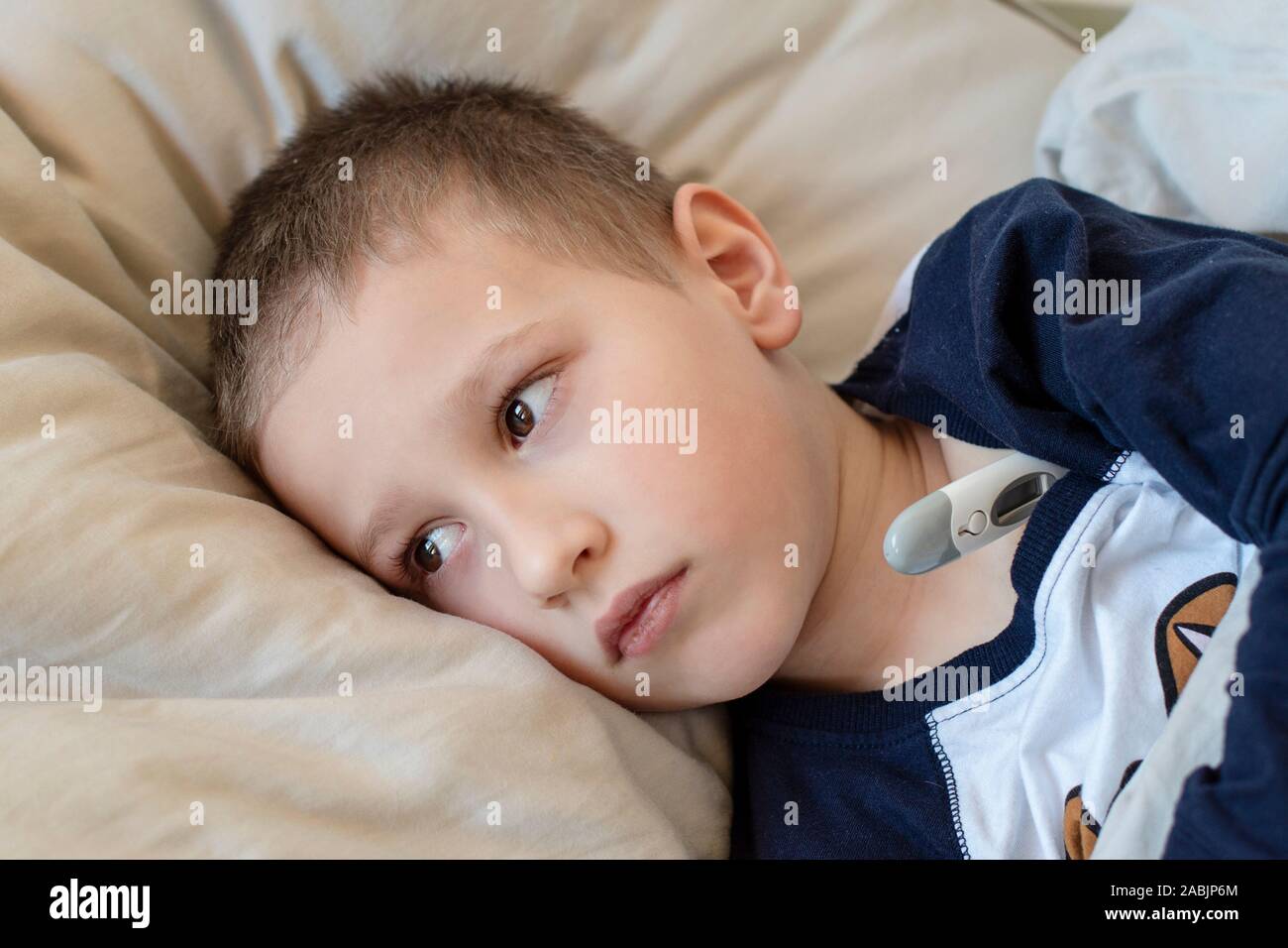 Pre-school sick boy in pyjama lying on pillow in bed with a digital  thermometer. Ill boy is measuring body temperature and doesn't feel well  Stock Photo - Alamy