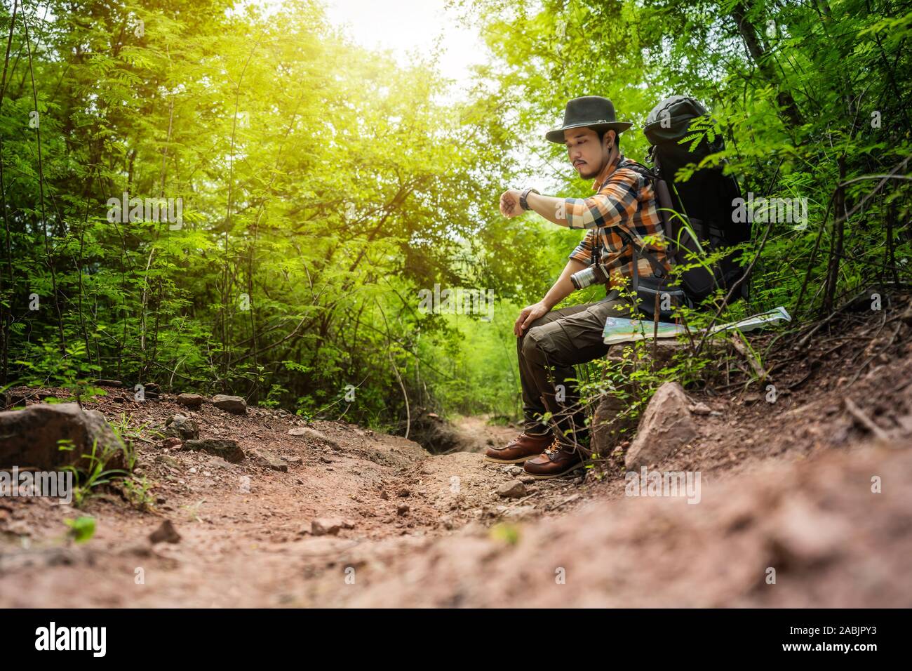 man traveler with backpack thinking and looking a wrist watch in the natural forest Stock Photo Alamy
