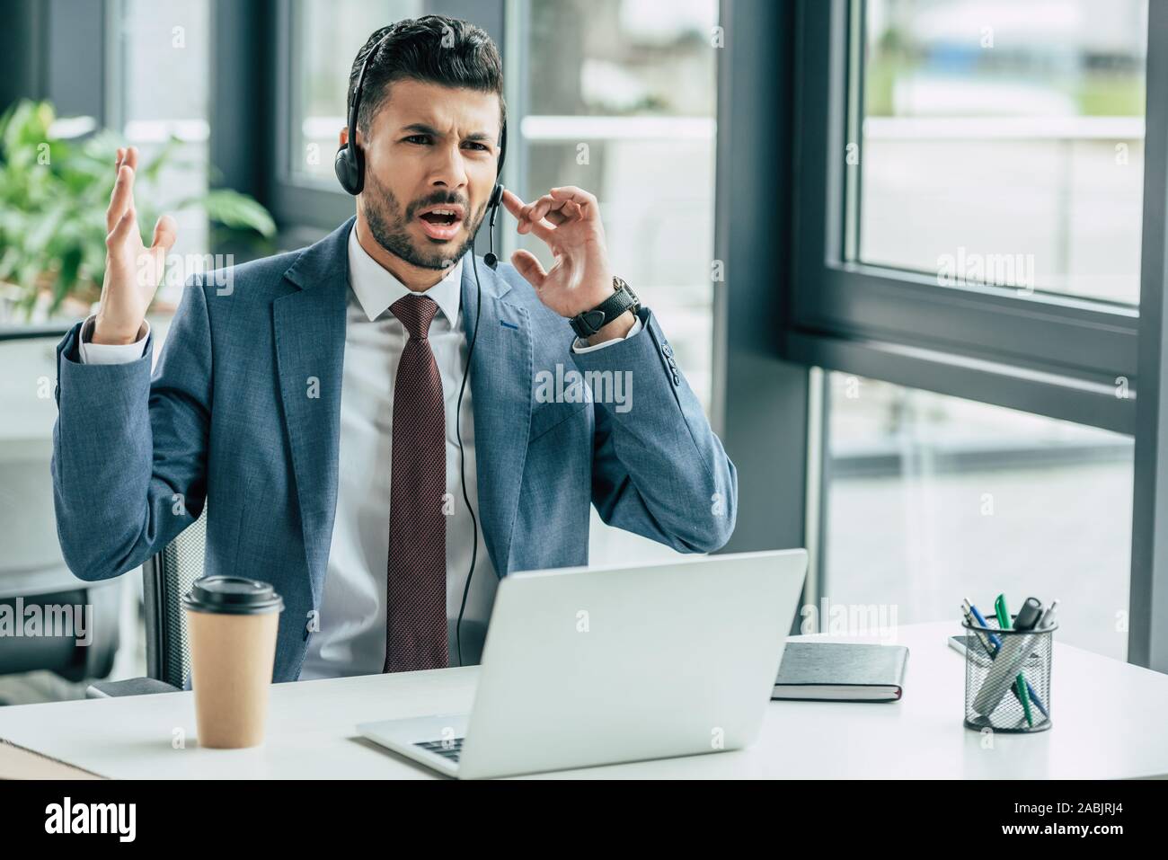 irritated call center operator in headset showing indignation gesture Stock Photo