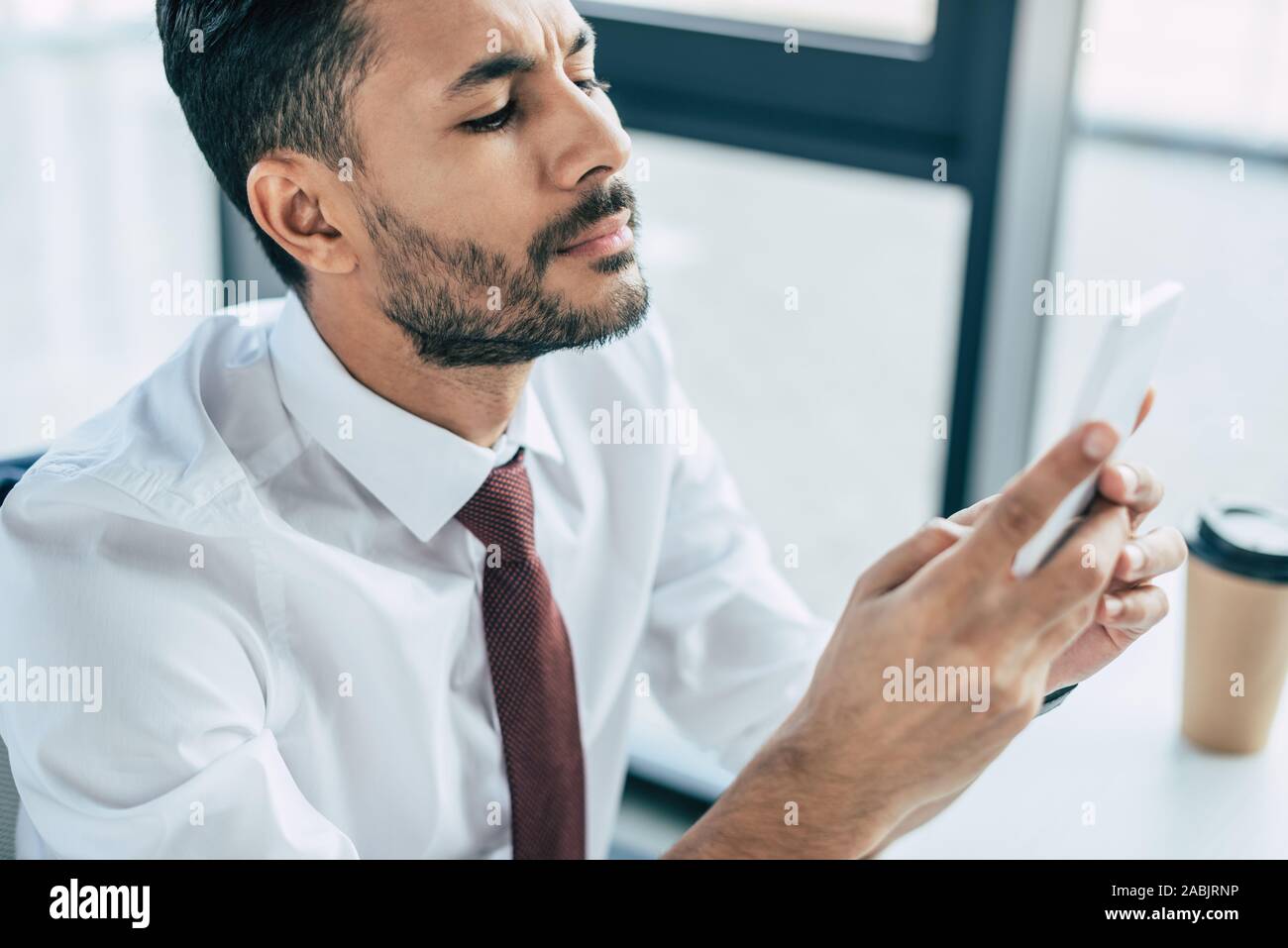thoughtful businessman using smartphone in office Stock Photo