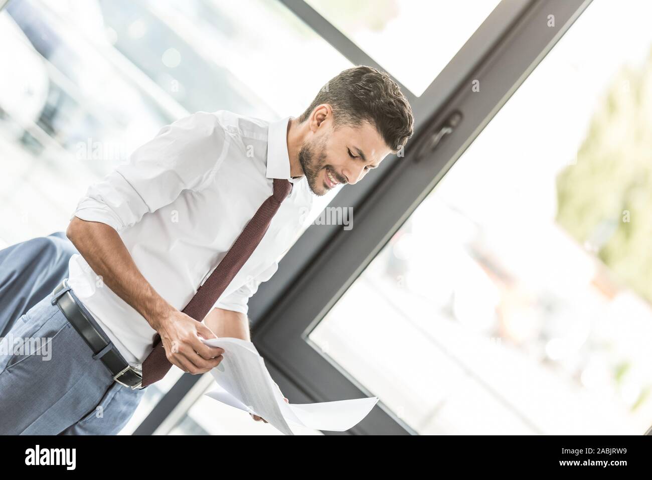 young businessman smiling while looking at papers in office Stock Photo