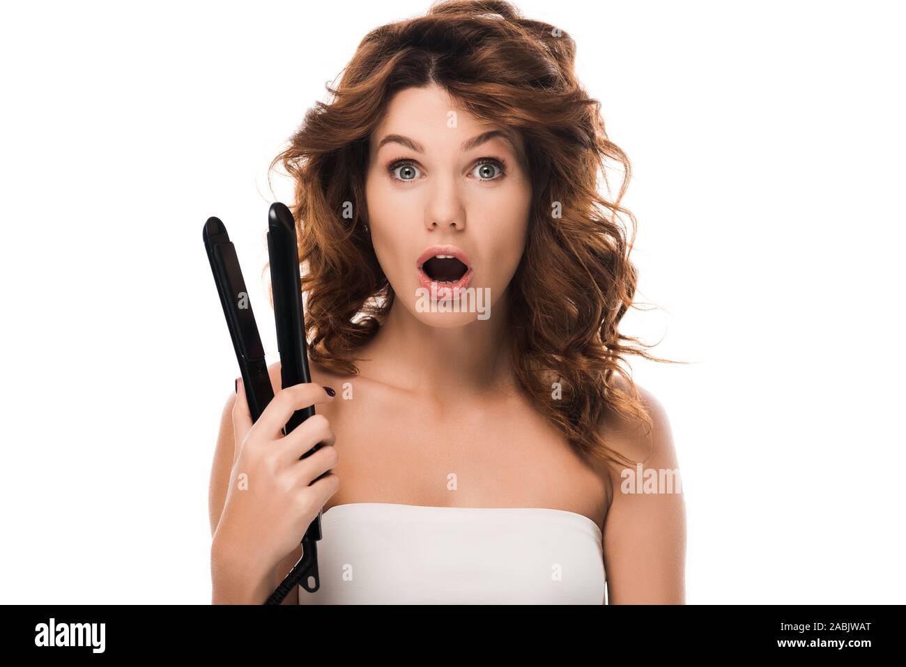 surprised curly girl holding hair iron isolated on white Stock Photo