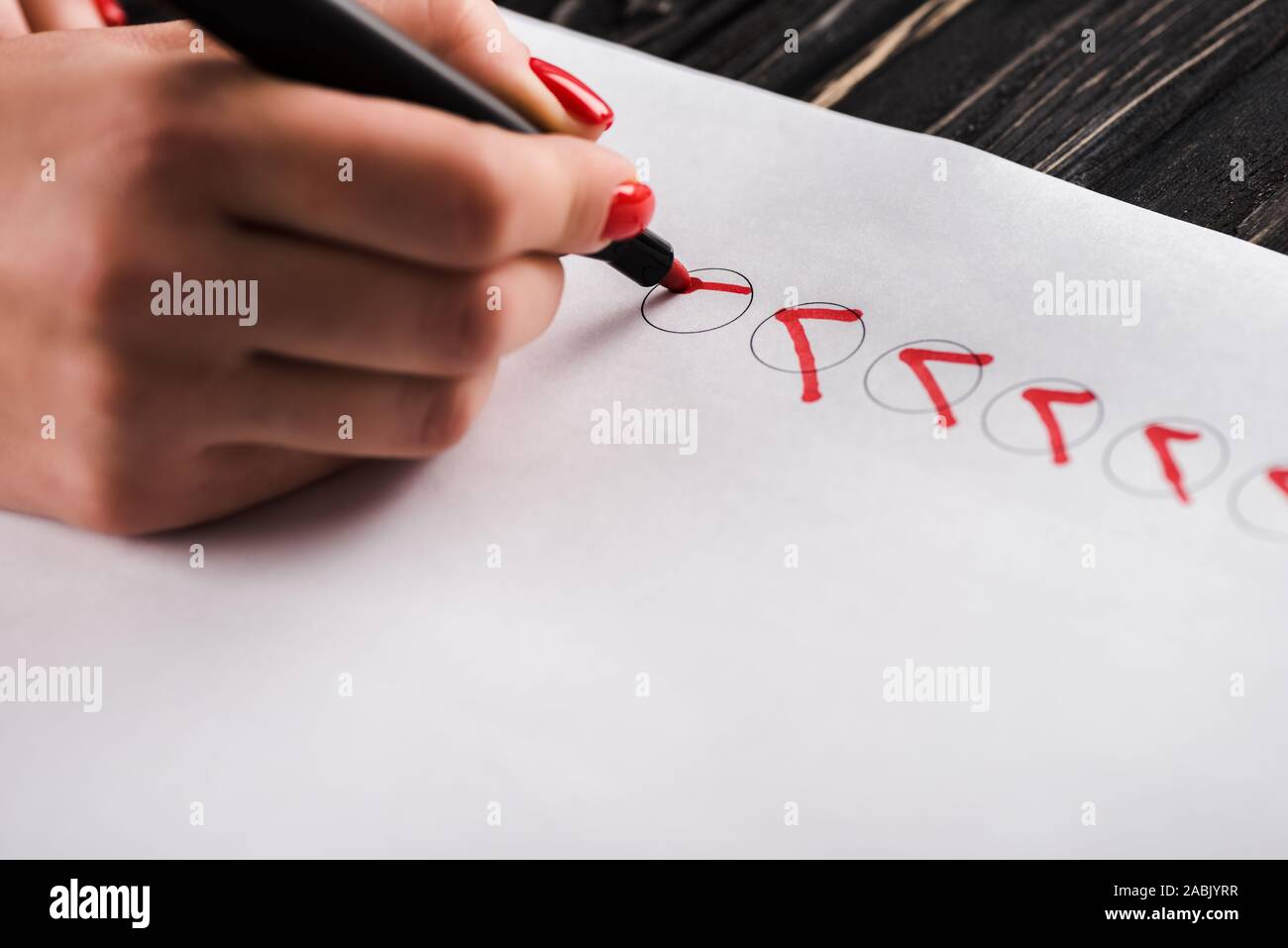 cropped view of woman holding marker pen near red ticks on paper Stock Photo