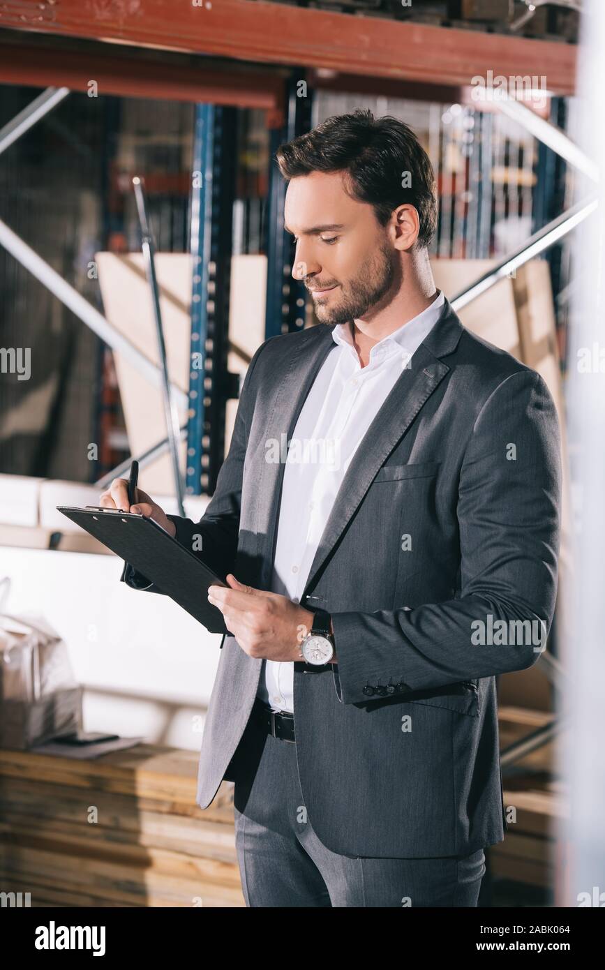 concentrated businessman writing on clipboard in warehouse Stock Photo ...