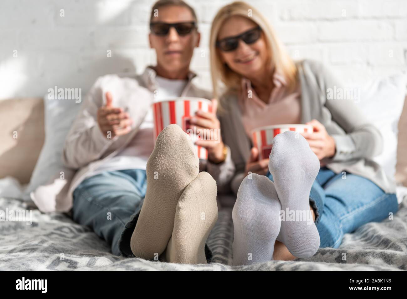 Selective focus on couple in 3d glasses with popcorn on bed Stock Photo