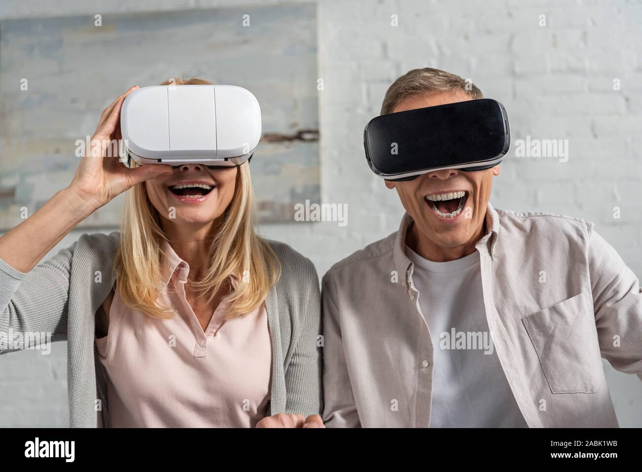 Laughing couple in virtual reality headsets at home Stock Photo - Alamy