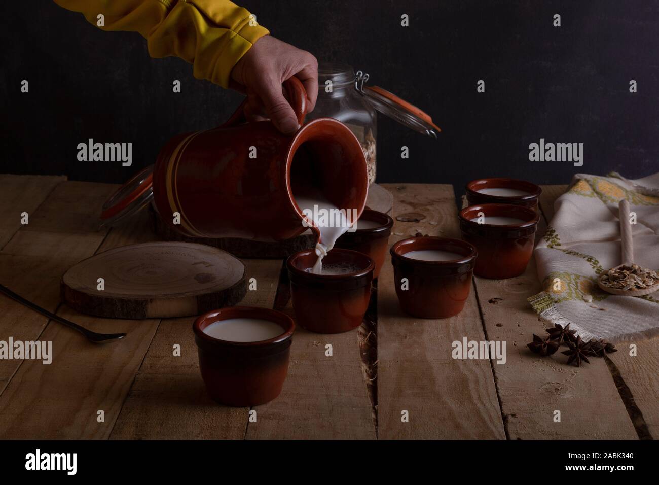 Serve milk for breakfast with a jug of clay in glasses of mud on a wooden table. Horizontal composition. Front view Stock Photo