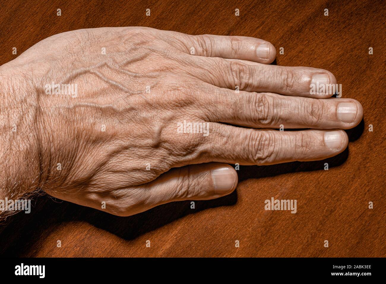 Color photo of a senior man left hand on a wooden background Stock Photo