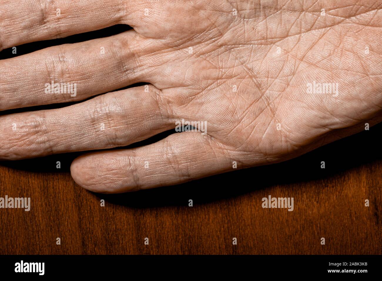 Picture of elderly male hands on a wooden background. Detail of the palm of the hand. Stock Photo