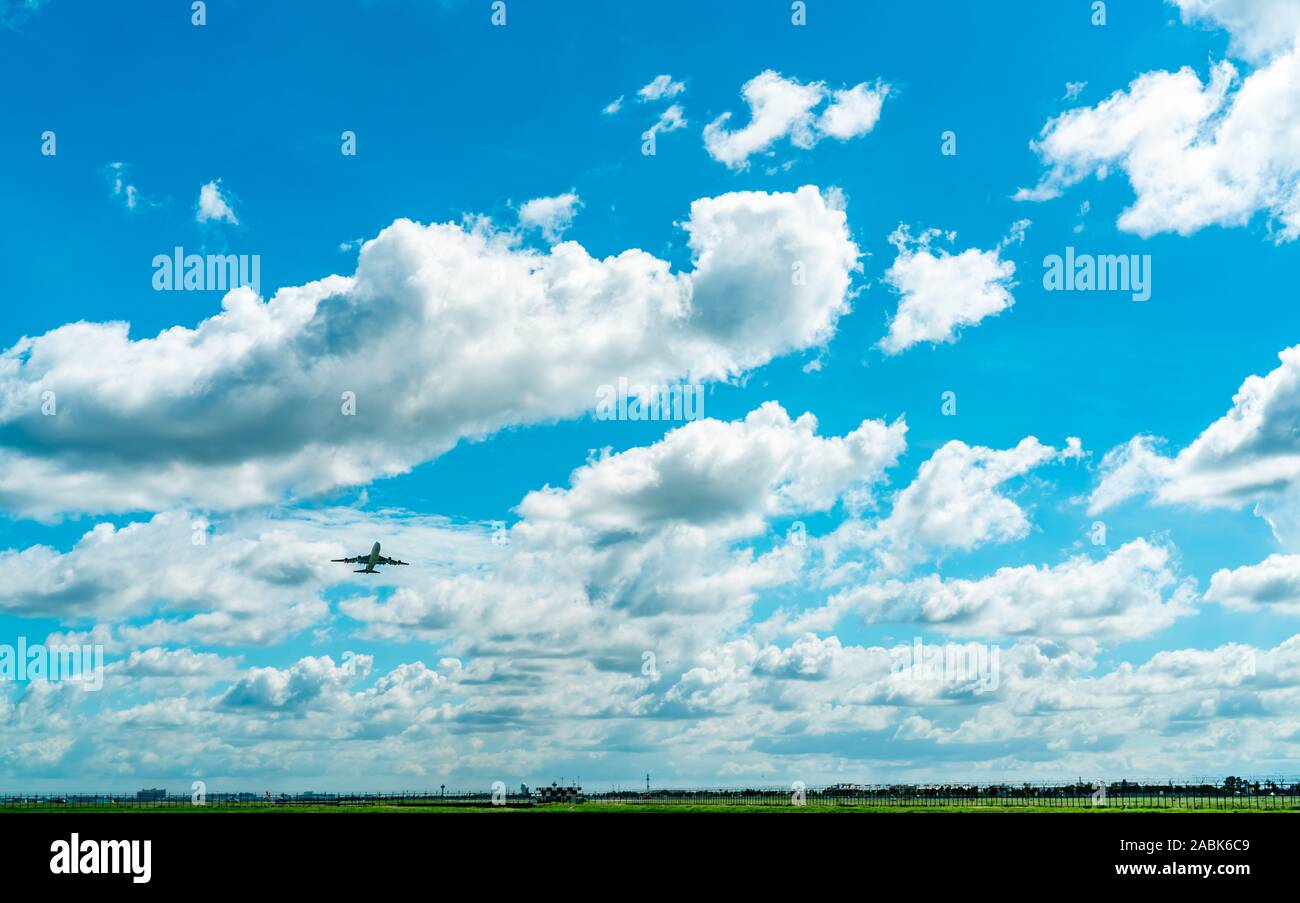 Commercial airline flying on blue sky and white fluffy clouds. Passenger plane after take off or going to landing flight. Vacation travel abroad. Air Stock Photo