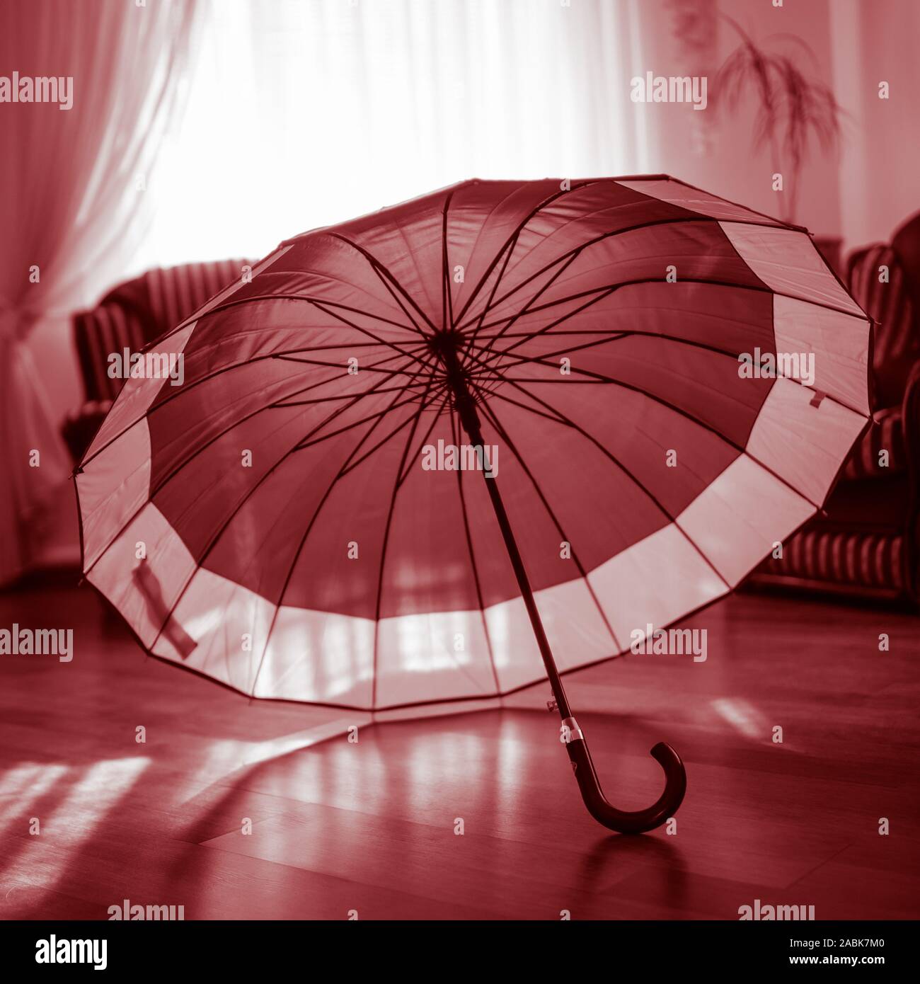 open umbrella standing on the laminate floor in the sunny room Stock