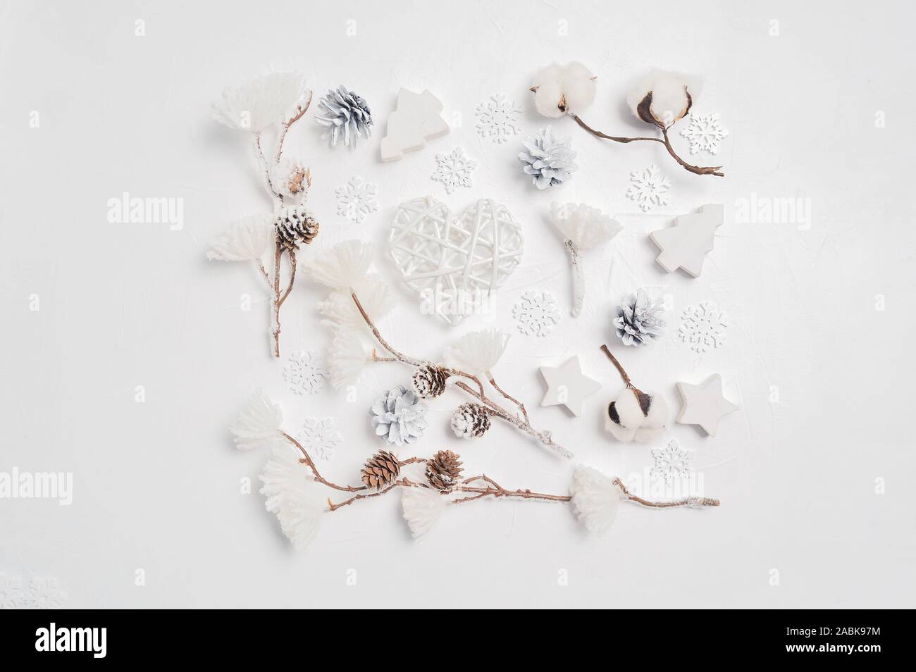 Design a Christmas greeting card with Xmas cones, heart, cotton flowers. Decorations on a white wooden background Stock Photo