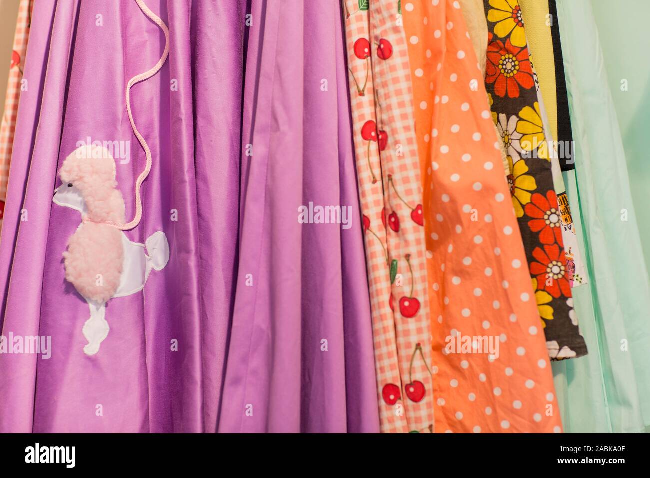 Sideview of colorful vintage skirts with different patterns, colors and textures hanging on a rack. Thrift, second hand, circular economy, recycle Stock Photo