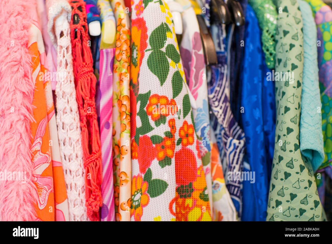 Sideview of some colorful vintage clothes with different patterns, colors and textures hanging on a rack. Thrift, second hand, circular economy, recyc Stock Photo
