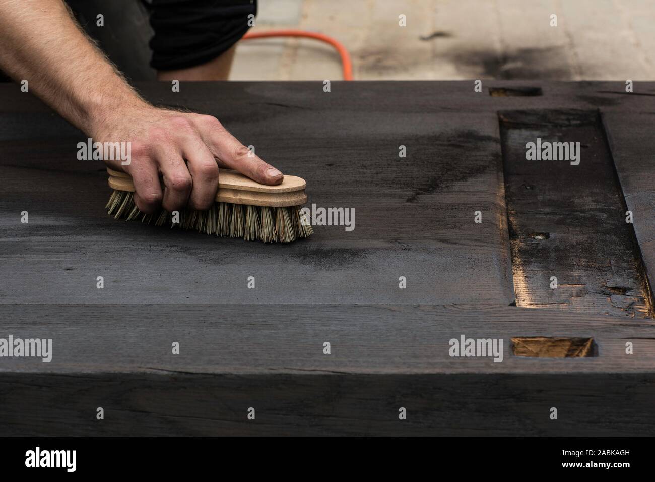 Dirty hand finishing and brushing burnt shou sugi ban wood brushing away the ashes on oak wood