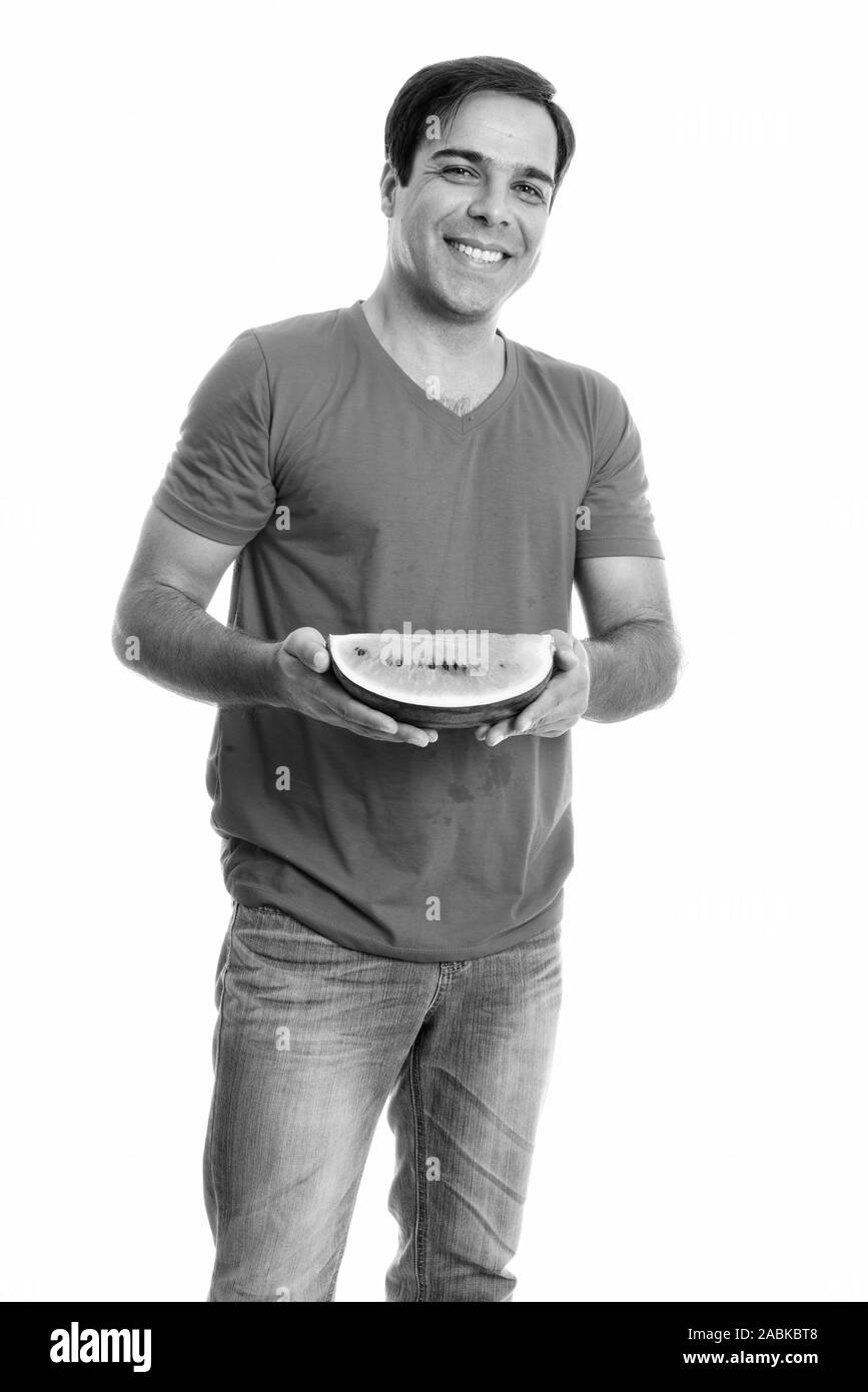 Young happy Persian man smiling and standing while holding slice of ...