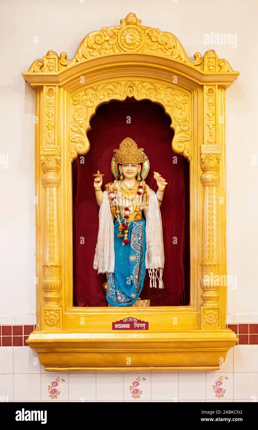 A statue if the Hindu deity Vishnu in an ornate gold frame on the wall of a temple on Liberty Ave. in South Richmond Hill, Queens, New York City. Stock Photo