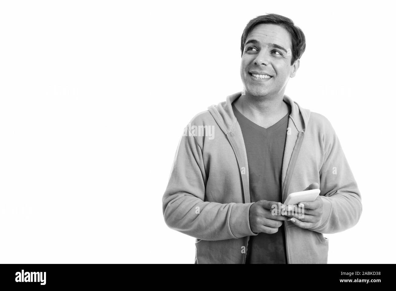 Studio shot of young happy Persian man smiling and thinking while ...