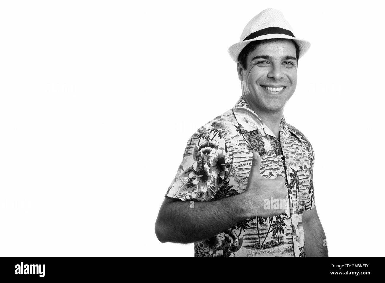 Studio shot of young happy Persian tourist man smiling while giving thumb up isolated against white background Stock Photo