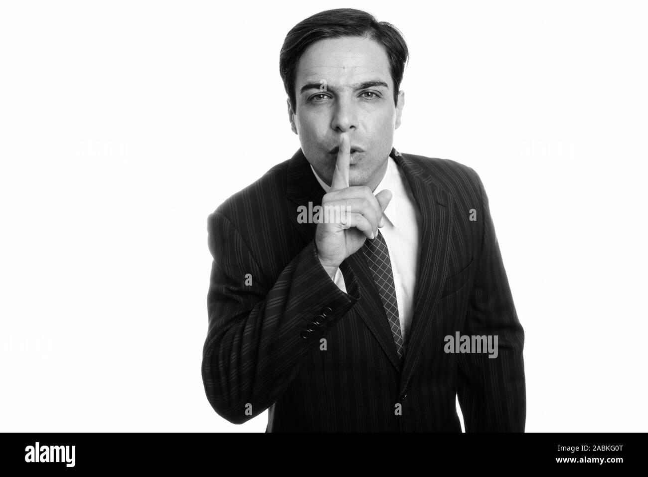 Studio shot of young Persian businessman with finger on lips isolated against white background Stock Photo