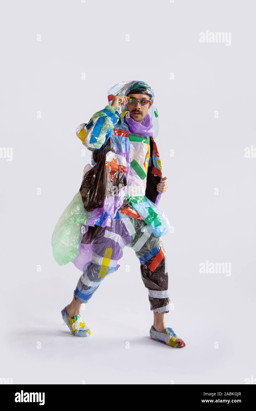 Man wearing plastic on white background. Male model in clothes made of  garbage. Fashion, style, recycling, eco and environmental concept. Too much  pollution, we're eating and taking it. Waste products Stock Photo -