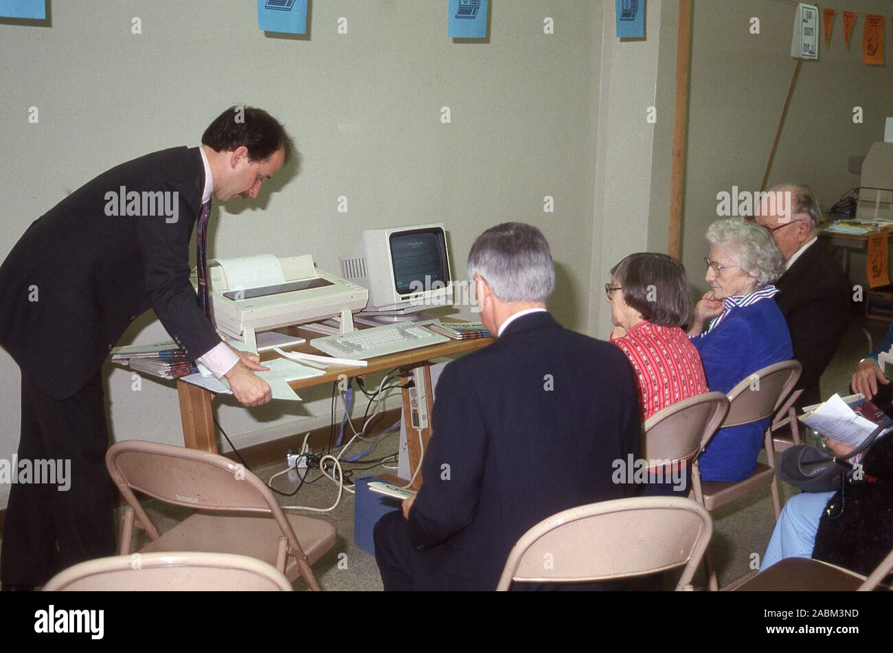 1988, a computer class for older adults....elderly people sitting in a room being given instructions on how to use a new computer terminal of the era with its keyboard and printer. The silent generation is generally known as people born between 1925 and 1945. Stock Photo