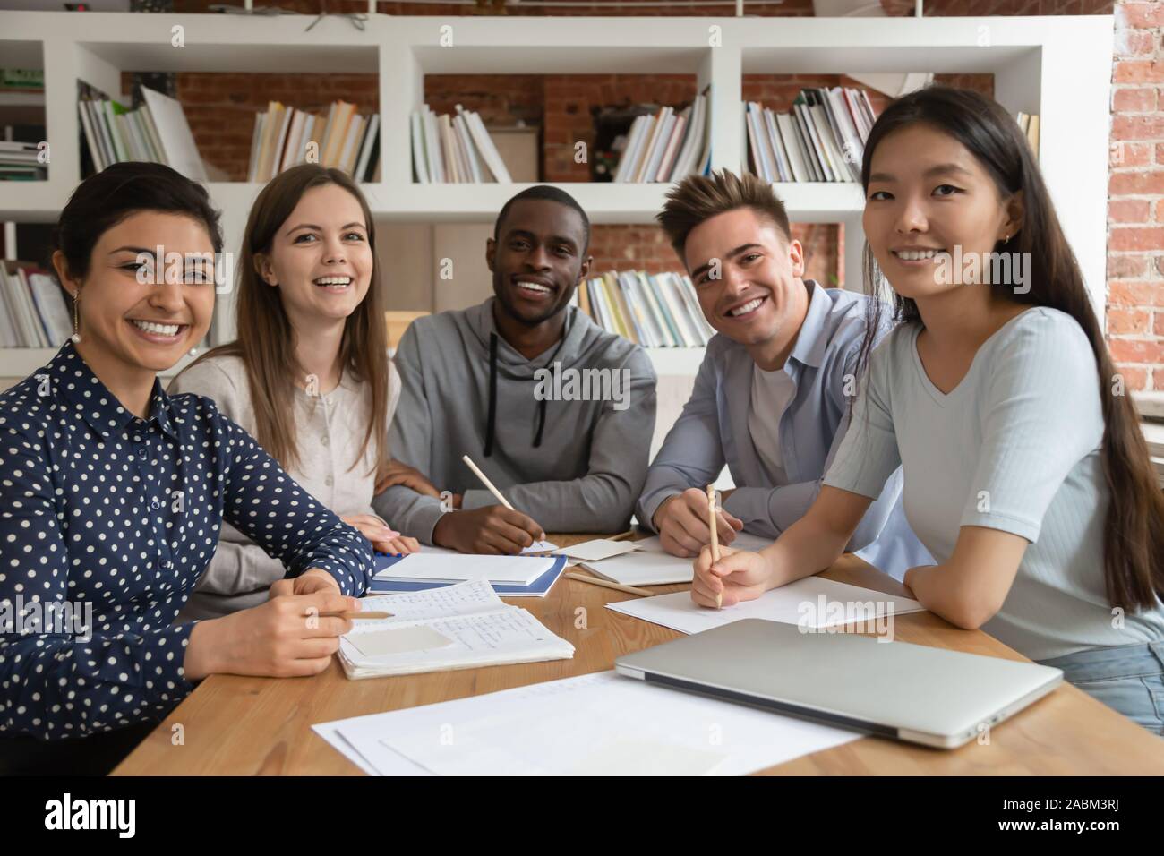 Happy mixed race students gathered in classroom, looking at camera. Stock Photo