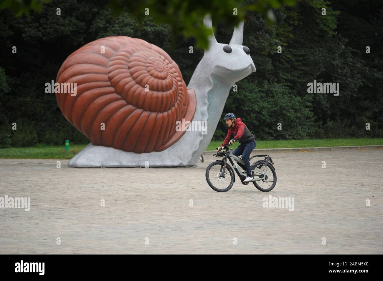 The snail sculpture "Sweet Brown Snail" in front of the traffic center of  the Deutsches Museum. In the foreground the High-End-E-Bike Superdelite GT  Rohloff HS of the manufacturer Riese und Müller. The
