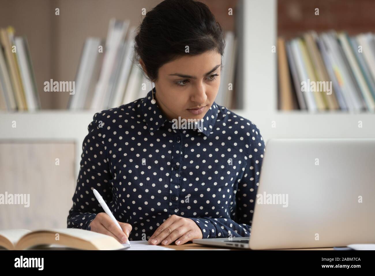 Concentrated indian female student reading scientific article. Stock Photo