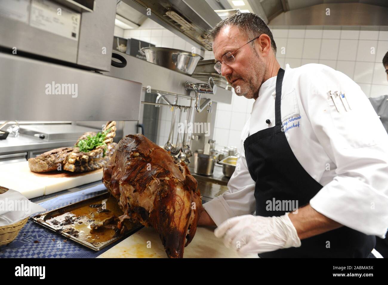 'Wirtshaus live': Chef Wolfgang Schmidt with a roasted Spanferkl in the kitchen of the restaurant 'Ayinger am Platzl'. [automated translation] Stock Photo