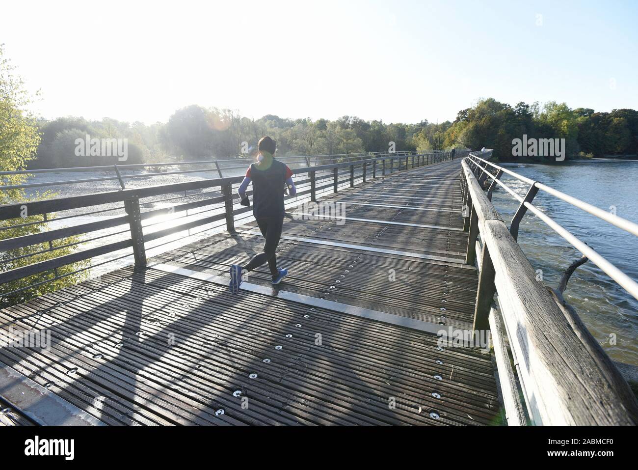 A jogger walks over the Flauchersteg on a sunny autumn day. [automated translation] Stock Photo