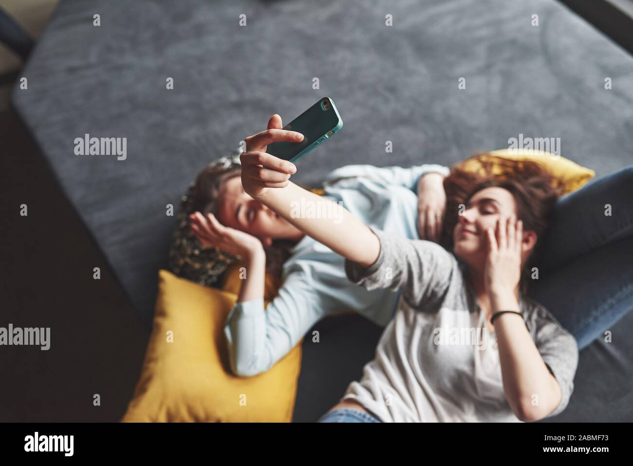 Two cute smiling twins sisters holding smartphone and making selfie 