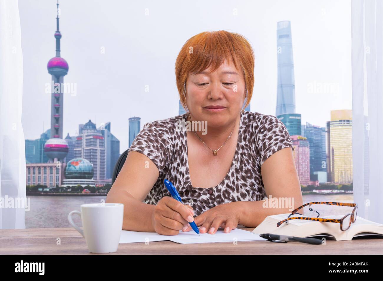 Asian woman in the office writing on a paper with a pen Stock Photo